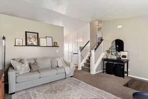 Carpeted living room featuring lofted ceiling and stairs