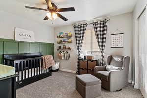 Bedroom with a nursery area, a closet, carpet flooring, and a ceiling fan