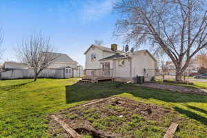 Back of house with a fenced backyard, a wooden deck, and a shed