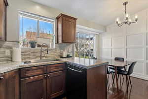 Kitchen with a decorative wall, black dishwasher, healthy amount of natural light, pendant lighting, and a chandelier