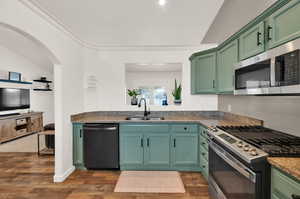 Kitchen featuring green cabinets, appliances with stainless steel finishes, dark stone countertops, dark wood finished floors, and vaulted ceiling