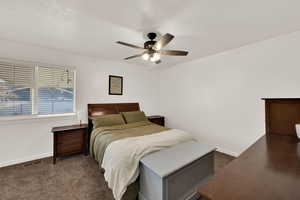 Bedroom with ceiling fan and dark carpet