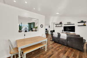 Living area with dark wood-style floors, recessed lighting, and ornamental molding