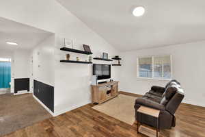 Living room featuring vaulted ceiling, healthy amount of natural light, and dark wood-style flooring