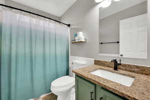 Full bath with a wainscoted wall, curtained shower, and vanity