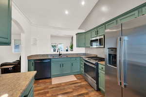 Kitchen featuring appliances with stainless steel finishes, green cabinetry, dark stone countertops, dark wood-style floors, and arched walkways