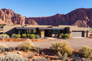 View of front of property featuring stucco siding, driveway, a mountain view, an attached garage, and stone siding