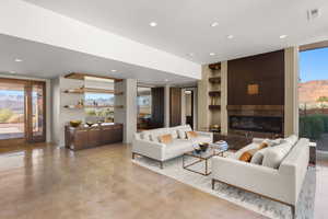 Living area featuring a mountain view, built in shelves, finished concrete flooring, a large fireplace, and recessed lighting