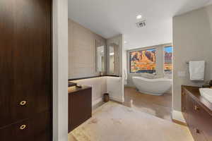 Bathroom with vanity, a freestanding bath, and recessed lighting