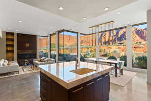 Kitchen featuring finished concrete flooring, light stone counters, a mountain view, expansive windows, and recessed lighting
