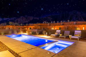 Pool at twilight with a patio area and a pool with connected hot tub