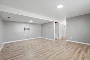 Basement with light wood-style floors and a textured ceiling
