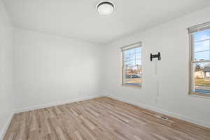 Unfurnished room featuring light wood finished floors and baseboards