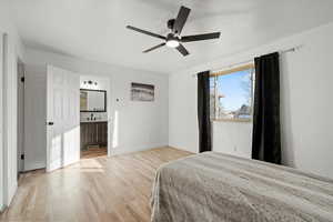 Bedroom with light wood-style flooring, a ceiling fan, and connected bathroom