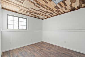 Spare room featuring dark wood-style floors and baseboards