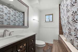 Bathroom with dark wood-type flooring, vanity, and tiled shower / bath combo