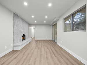 Unfurnished living room with light wood finished floors, a fireplace, and recessed lighting
