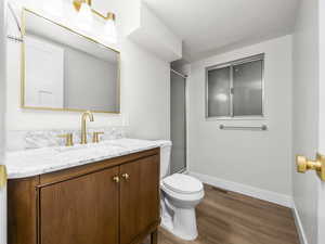 Bathroom featuring vanity, a shower with door, and dark wood-style floors