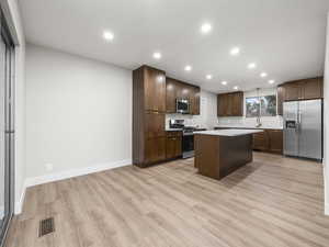 Kitchen with a kitchen island, stainless steel appliances, recessed lighting, dark brown cabinetry, and light wood-style floors