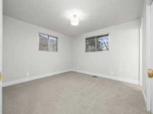 Unfurnished room featuring light carpet and baseboards