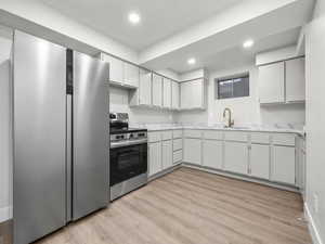 Kitchen with light countertops, stainless steel appliances, light wood-style flooring, white cabinetry, and recessed lighting