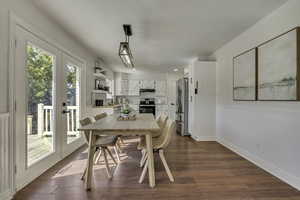 Dining space featuring dark wood-type flooring, wainscoting, and french doors