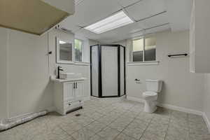 Bathroom featuring vanity, a stall shower, a drop ceiling, and light tile patterned floors