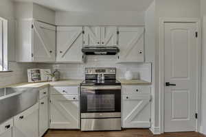 Kitchen with stainless steel electric range and white cabinetry