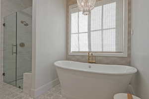 Full bath featuring a stall shower, a freestanding bath, and a chandelier