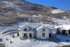 Snow covered back of property featuring a mountain view and a porch