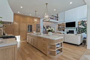 Kitchen featuring pendant lighting, ventilation hood, light wood-style floors, a fireplace, and recessed lighting