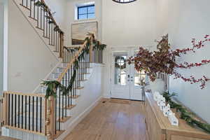 Foyer entrance with a high ceiling, french doors, light wood finished floors, and stairway
