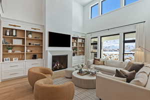 Living area featuring a towering ceiling, a lit fireplace, and light wood finished floors