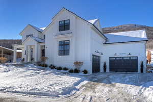 Modern farmhouse style home with board and batten siding, a garage, concrete driveway, and a porch