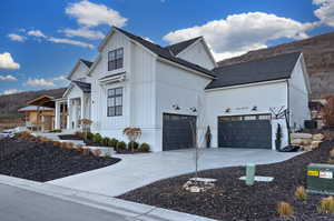View of side of property with board and batten siding, concrete driveway, a shingled roof, and an attached garage