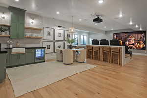 Kitchen featuring green cabinets, open shelves, beverage cooler, recessed lighting, and light wood-style floors