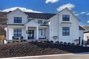 View of front of home featuring board and batten siding, covered porch, a shingled roof, and a standing seam roof