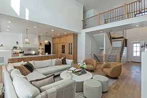 Living room with a towering ceiling, light wood-style floors, stairs, and recessed lighting