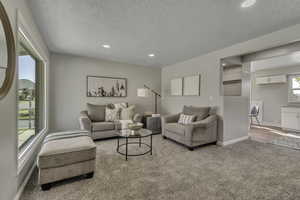 Living room with light carpet, a textured ceiling, and recessed lighting