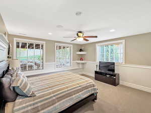 Bedroom featuring light colored carpet, ceiling fan, recessed lighting, and wainscoting