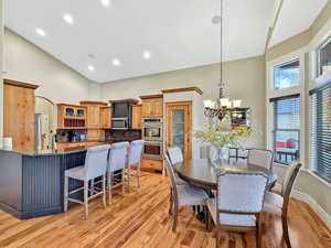 Dining area featuring high vaulted ceiling, light wood-style flooring, a chandelier, arched walkways, and recessed lighting