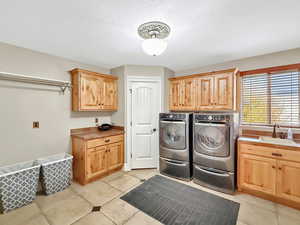 Washroom featuring cabinet space, washing machine and clothes dryer, a textured ceiling, and light tile patterned floors