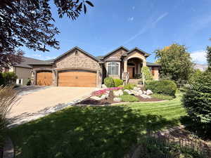 Craftsman-style home featuring a front lawn, an attached garage, concrete driveway, and stone siding