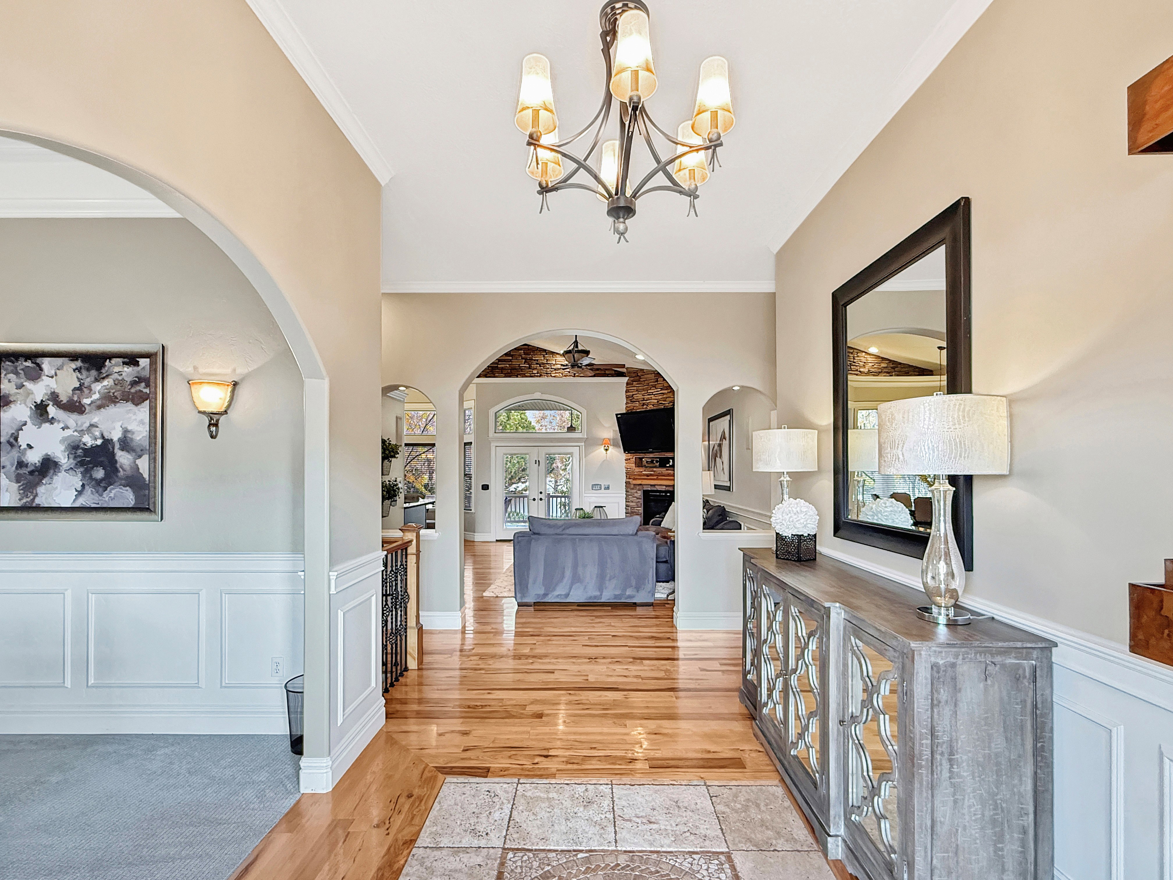 Entrance foyer featuring a wainscoted wall, a decorative wall, arched walkways, ornamental molding, and light wood-style floors