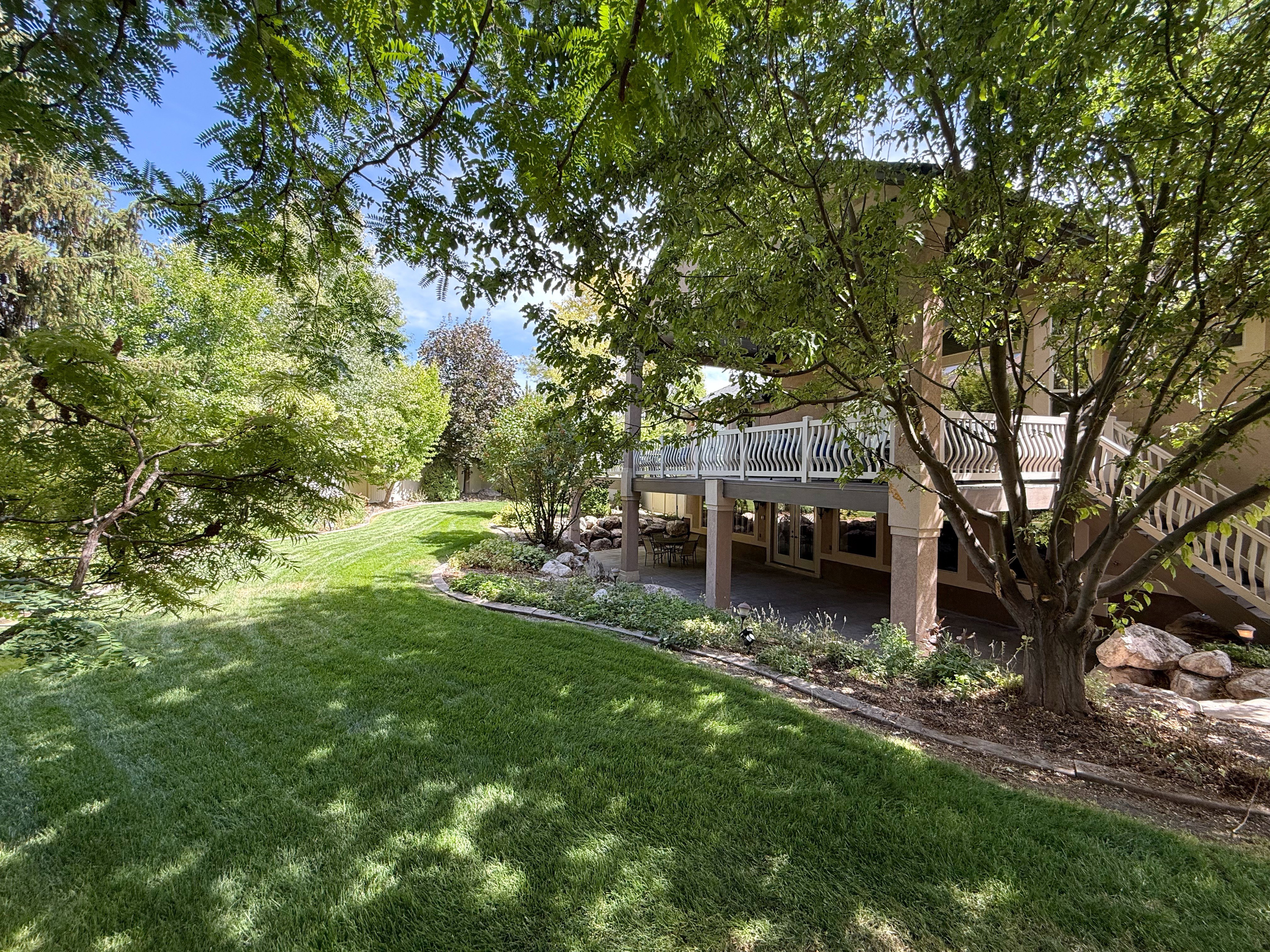 View of green lawn with a patio area and a deck
