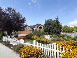 Obstructed view of property with a fenced front yard, driveway, a garage, and stone siding