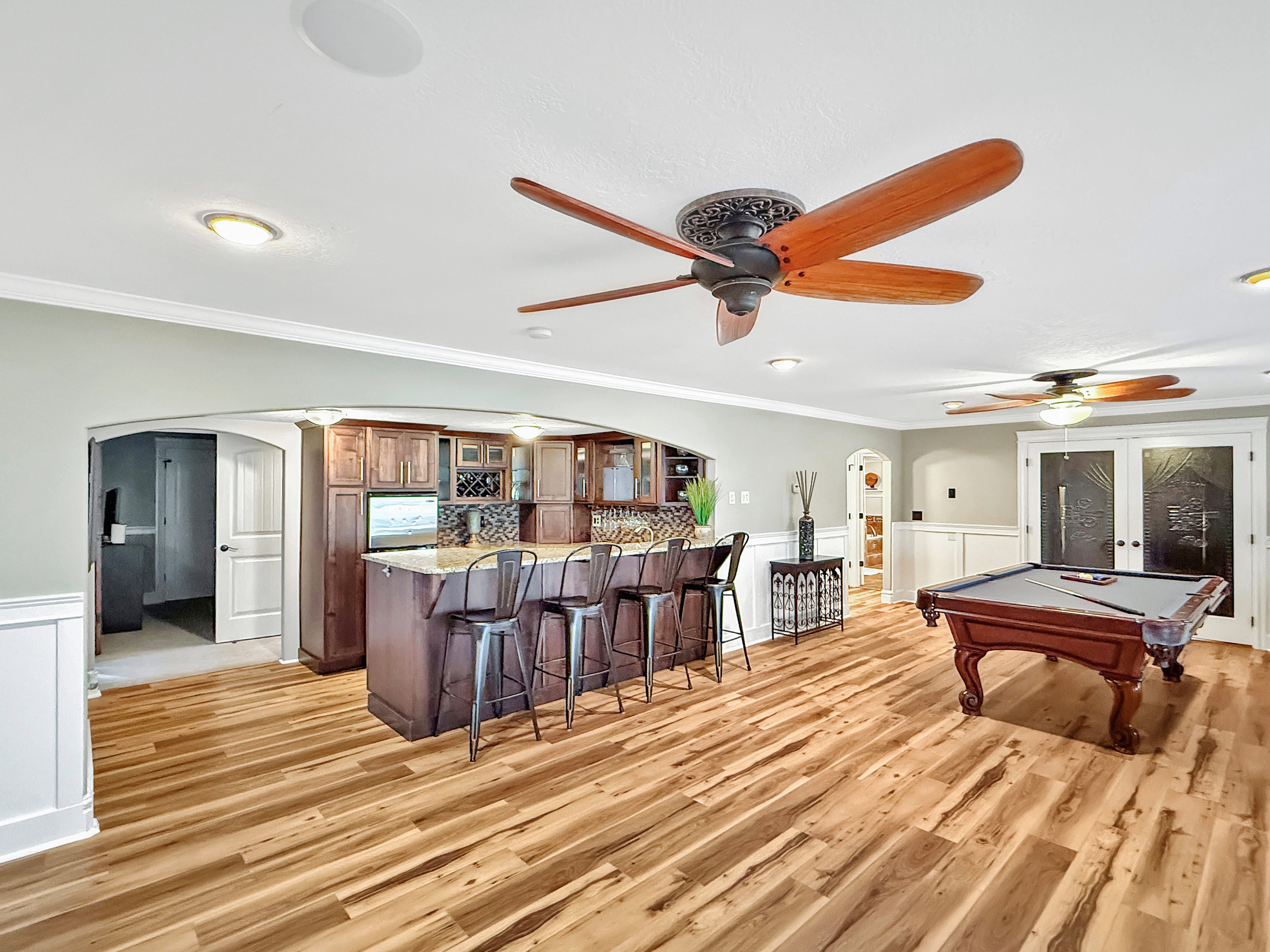 Playroom featuring arched walkways, a wainscoted wall, a decorative wall, billiards table, and crown molding