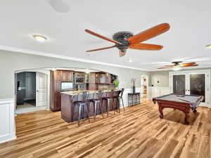 Playroom featuring arched walkways, a wainscoted wall, a decorative wall, billiards table, and crown molding