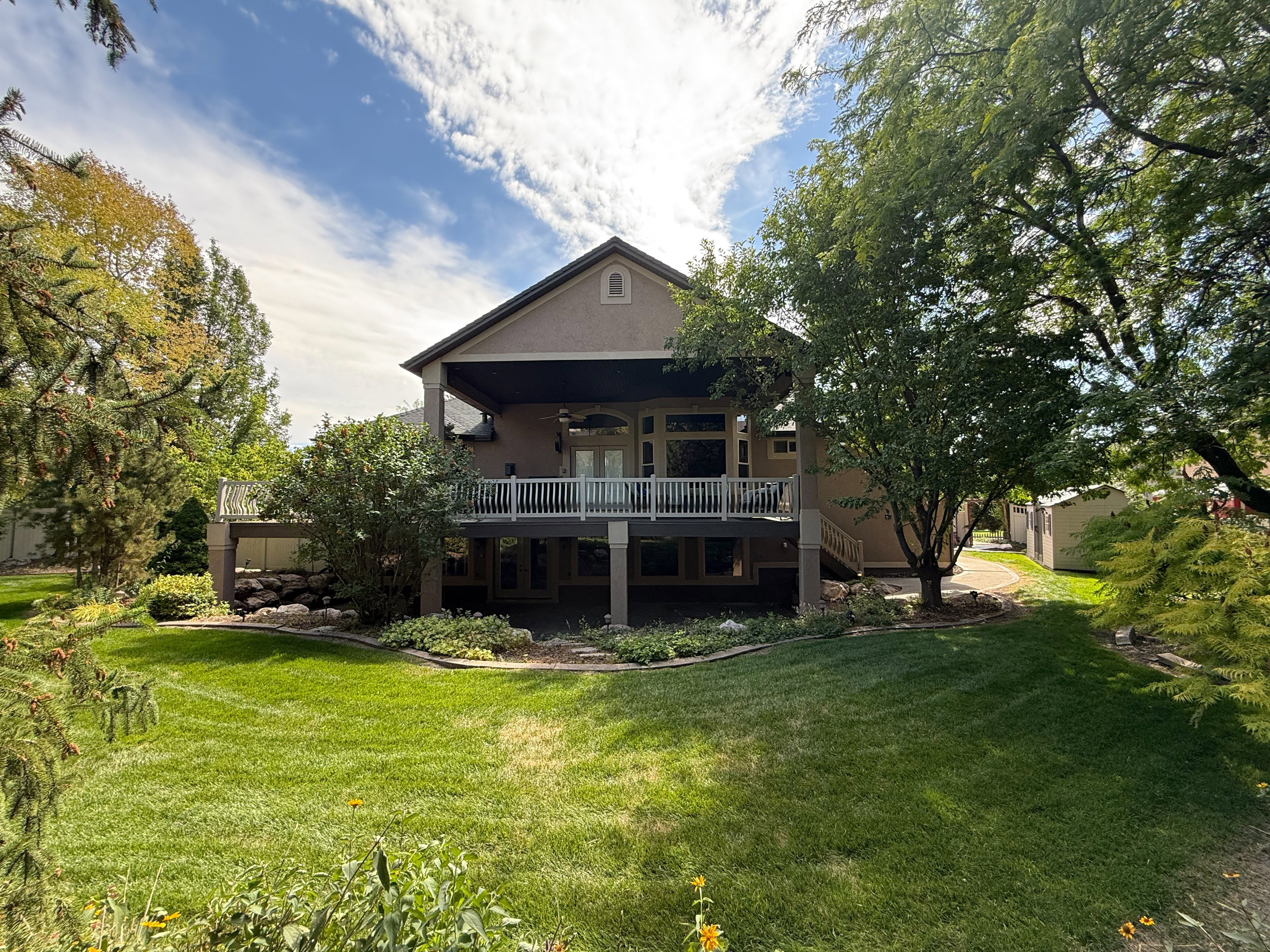Back of property featuring stucco siding, a yard, a deck, and ceiling fan