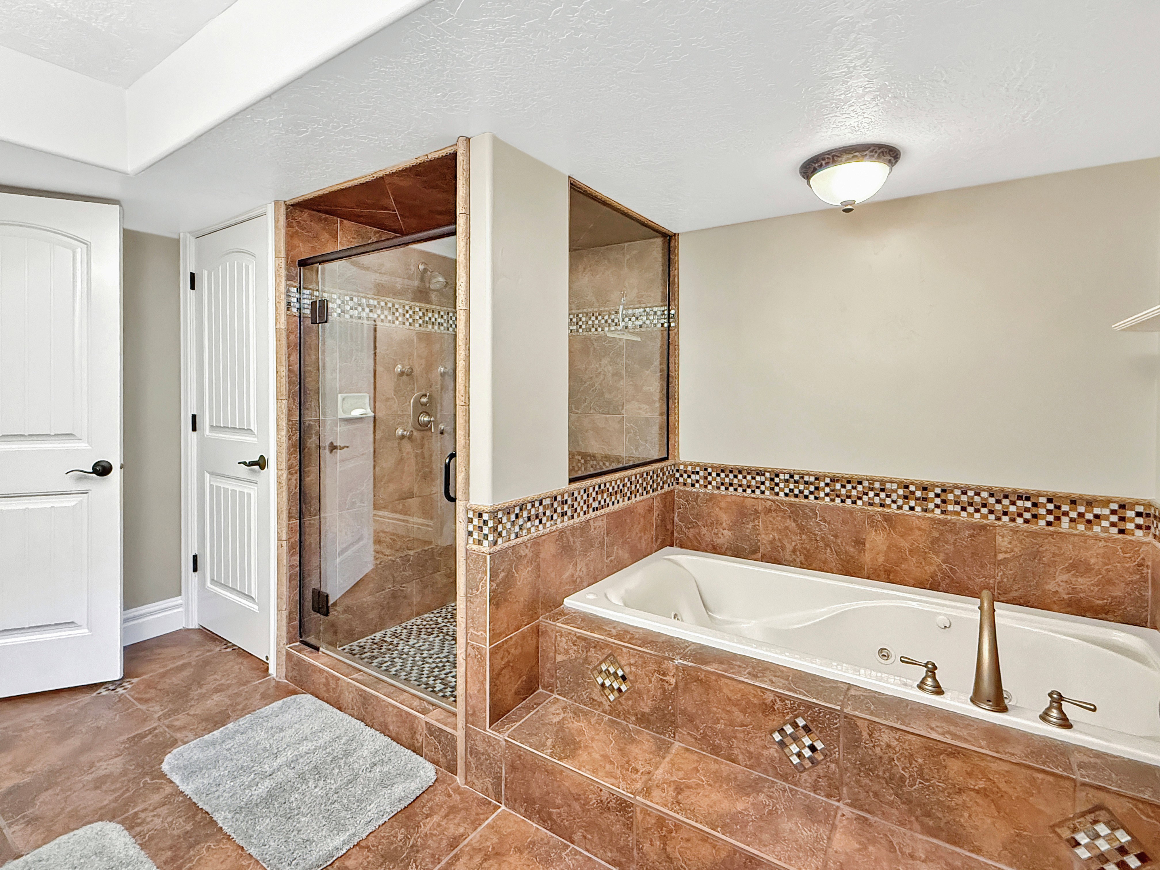 Full bath with a textured ceiling, a tub with jets, a stall shower, and tile patterned floors